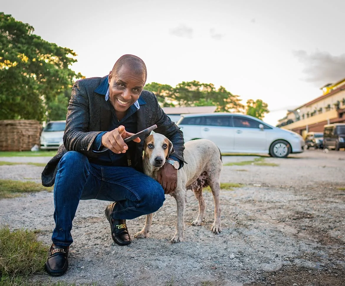 Peter Perry outdoors with a dog near Perry's vehicles