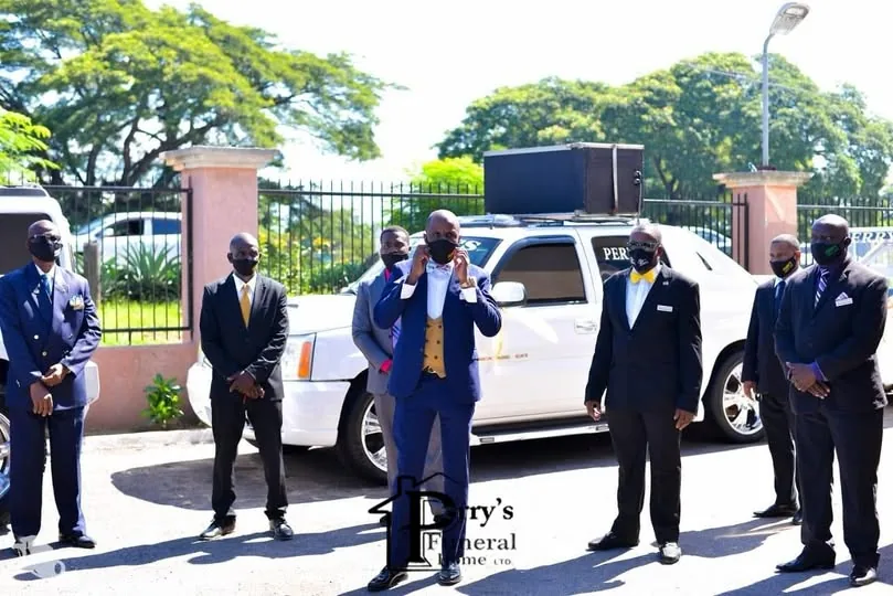 Perry's funeral team standing beside a white service vehicle